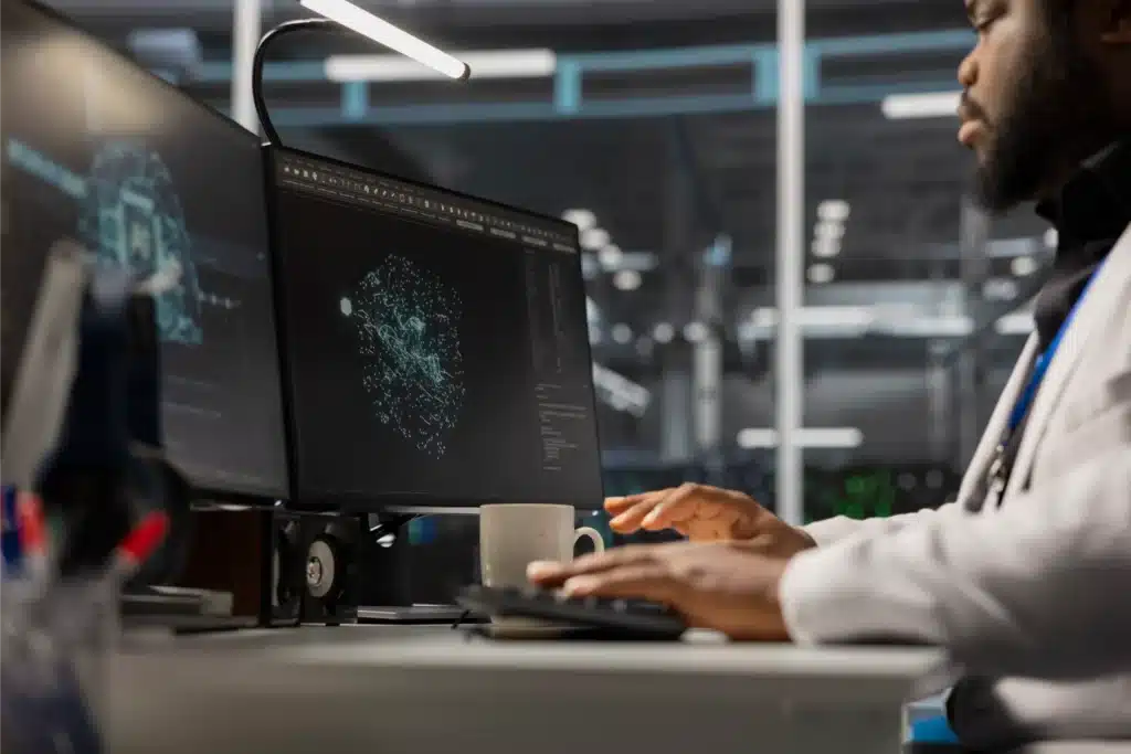 Mantenimiento predictivo: cómo la inteligencia artificial evita averías en la industria 3 Profesional trabajando frente a dos monitores con gráficos y datos digitales