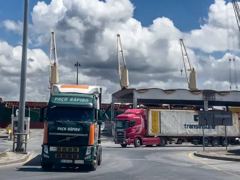 Comercio internacional: cómo funciona y qué oportunidades ofrece a las empresas 3 Camiones de mercancías estacionados junto a las grúas de un puerto marítimo