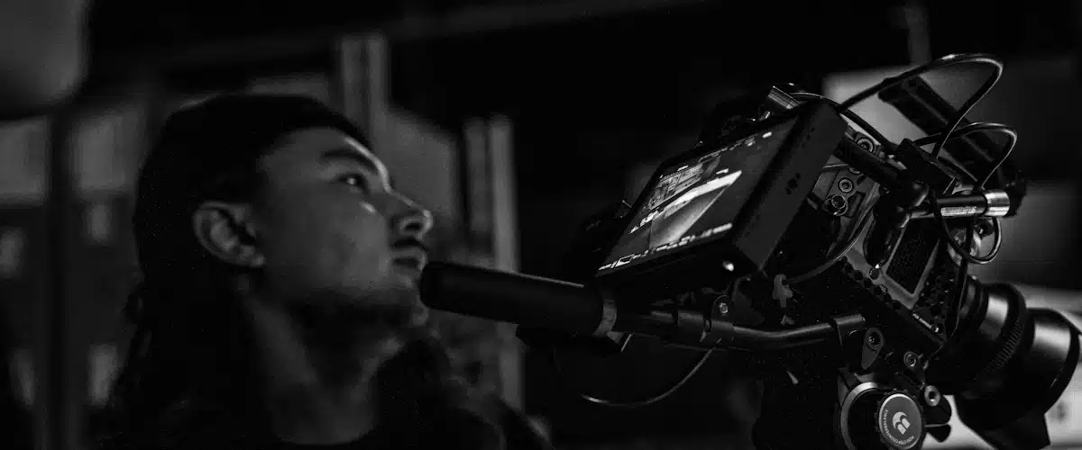 Producción audiovisual: fases, equipos y planificación de un proyecto 7 Cineasta junto a una cámara sobre trípode durante el rodaje de una escena