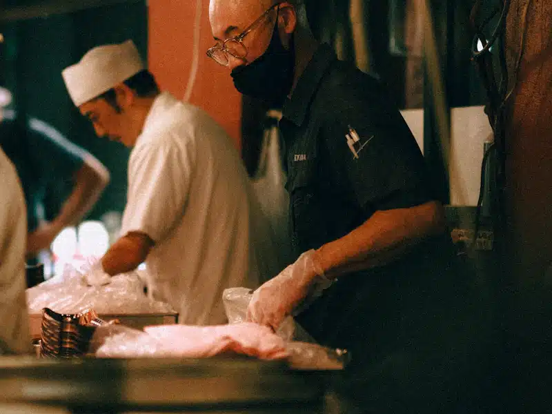 Seguridad alimentaria: controles y medidas para garantizar la calidad de los alimentos 3 Cocineros con guantes preparan alimentos en una cocina profesional organizada