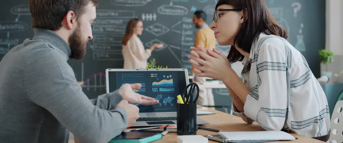 Branding: cómo construir una marca reconocible y diferenciada 8 Dos compañeros analizan gráficos en un portátil durante una reunión de trabajo