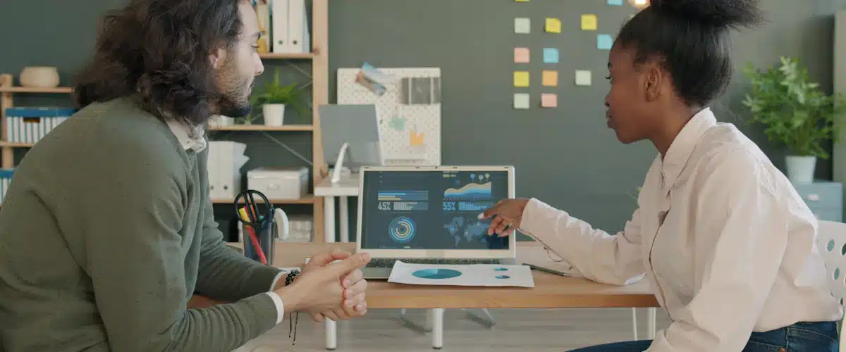 Inteligencia de negocio: cómo utilizar los datos para mejorar los resultados 6 Dos compañeros comparan indicadores de ventas en la pantalla de un portátil