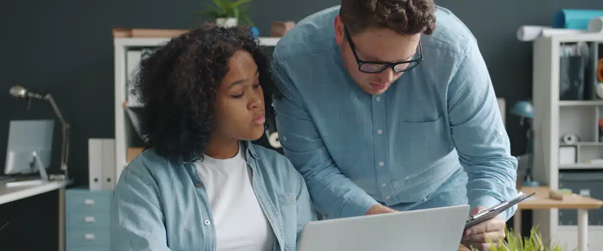 Atención al cliente: 7 estrategias para mejorar la experiencia 7 Dos profesionales conversan ante un portátil para resolver una incidencia