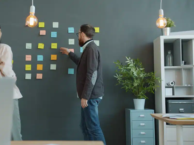 Branding: cómo construir una marca reconocible y diferenciada 3 Dos profesionales organizando ideas con notas adhesivas en una oficina luminosa