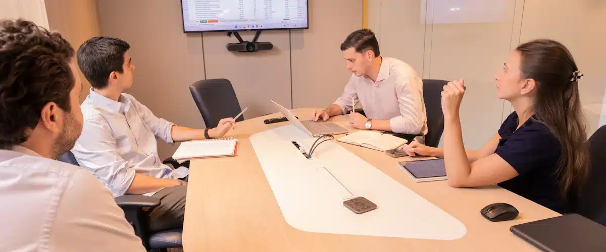 Valor presente neto: cómo calcularlo y decidir si invertir 8 Equipo reunido alrededor de una mesa para valorar alternativas de inversión