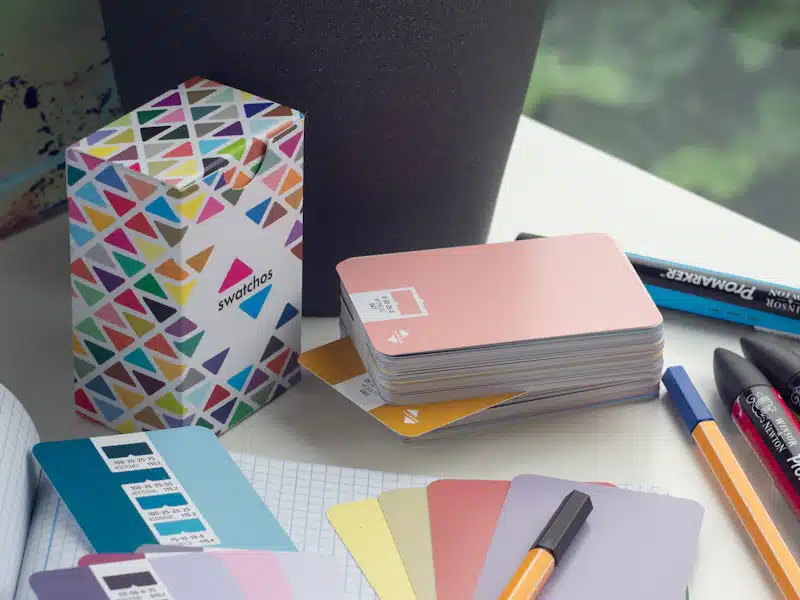 Identidad visual corporativa: elementos para construir una marca coherente 3 Mesa de diseño con cuaderno, rotuladores y tarjetas de colores ordenadas