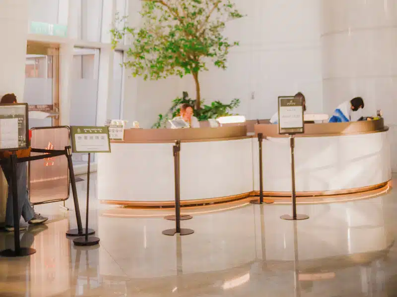 Atención al cliente: 7 estrategias para mejorar la experiencia 3 Mostrador de recepción con personal y visitantes en un espacio luminoso