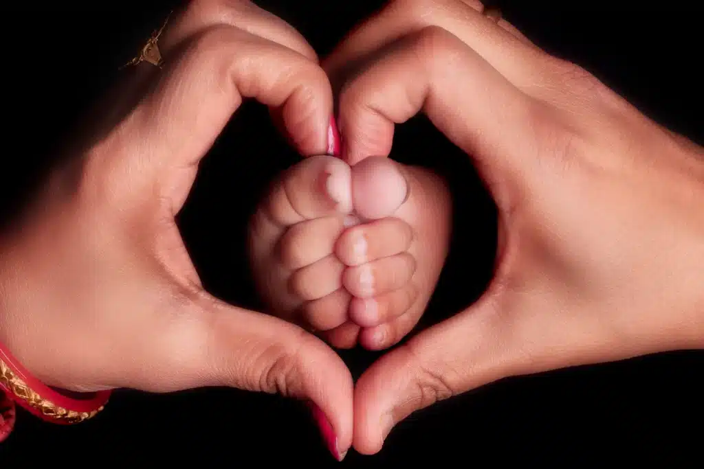 100 nombres de niña con significado: ideas para elegir en 2026 9 Manos formando un corazón alrededor de los pies de un bebé