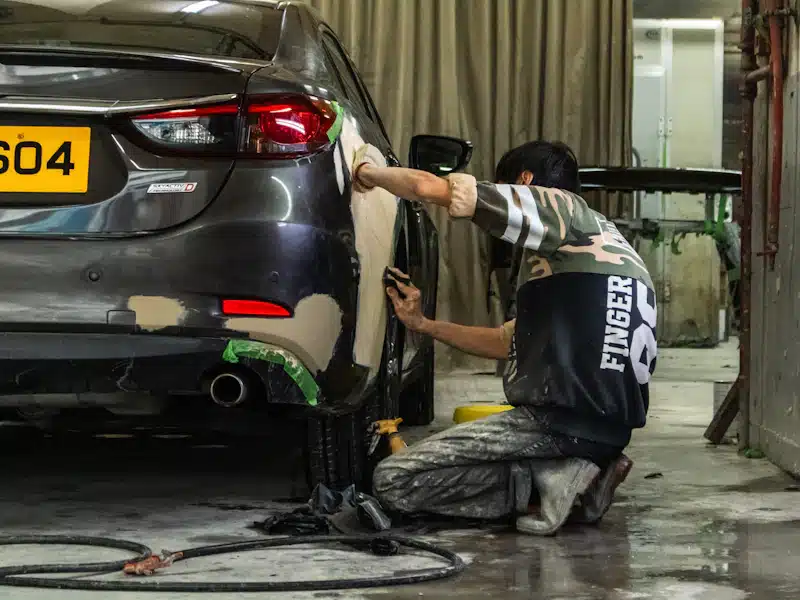 Chapa y pintura: 7 claves para un acabado perfecto 3 Técnico lijando un panel de carrocería con zonas de masilla visibles