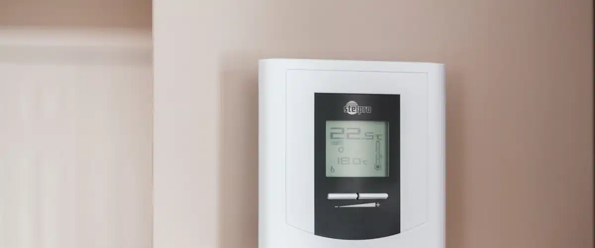 Termostato digital blanco mostrando la temperatura de calefacción en una pared